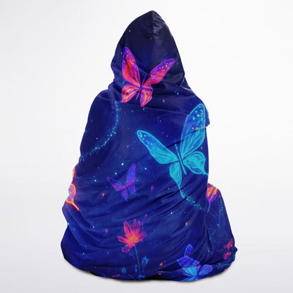 Butterfly Hooded Blanket 45x60 – soft fleece hooded blanket featuring glowing neon butterflies in vibrant blue, pink, and purple tones floating over a cosmic night-sky background full of stars and floral sparkles. Perfect for teens, butterfly lovers, cozy nights