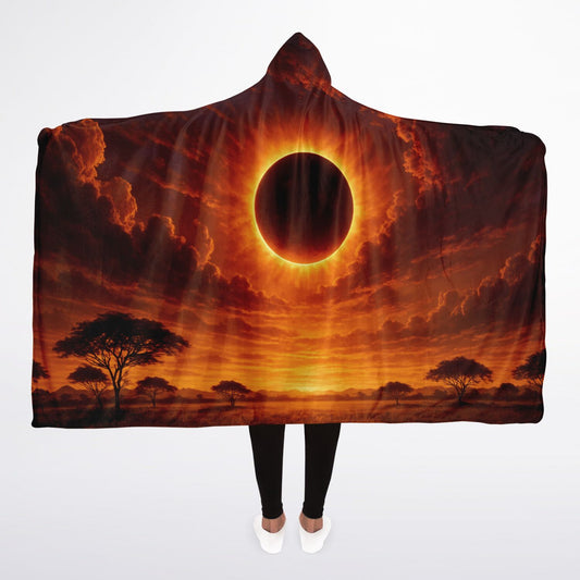 Eclipse of the Soul Hooded Blanket in size 45x60 featuring a dramatic golden solar eclipse shining over dark clouds, displayed outdoors on a wooden deck — premium cozy fleece blanket with celestial fire artwork for astrology and sky lovers